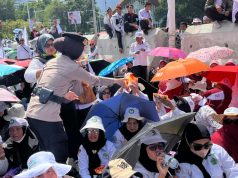 Polisi Bagikan Air Mineral dan Roti kepada Massa Aksi Damai Guru di Silang Selatan Monas