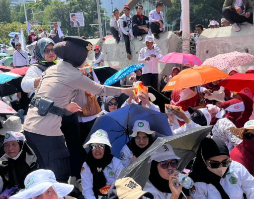 Polisi Bagikan Air Mineral dan Roti kepada Massa Aksi Damai Guru di Silang Selatan Monas