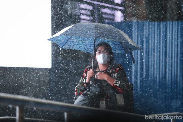 Seorang warga menggunakan payung saat hujan basahi Jakarta